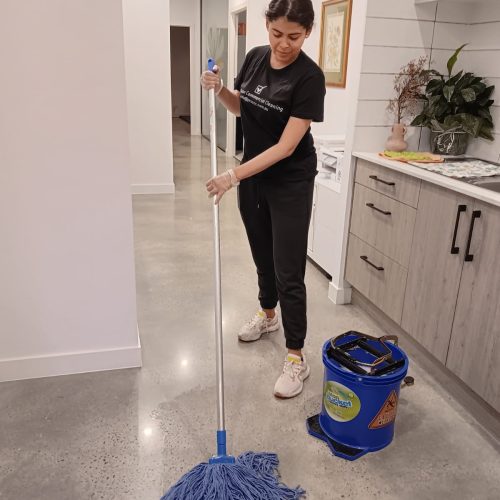 Cleaning professional Tatiana mopping clinic floor near staff zone